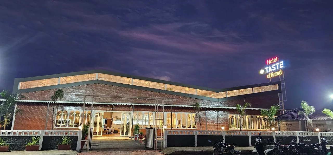Hotel Taste of Karad lit up at night with the neon sign